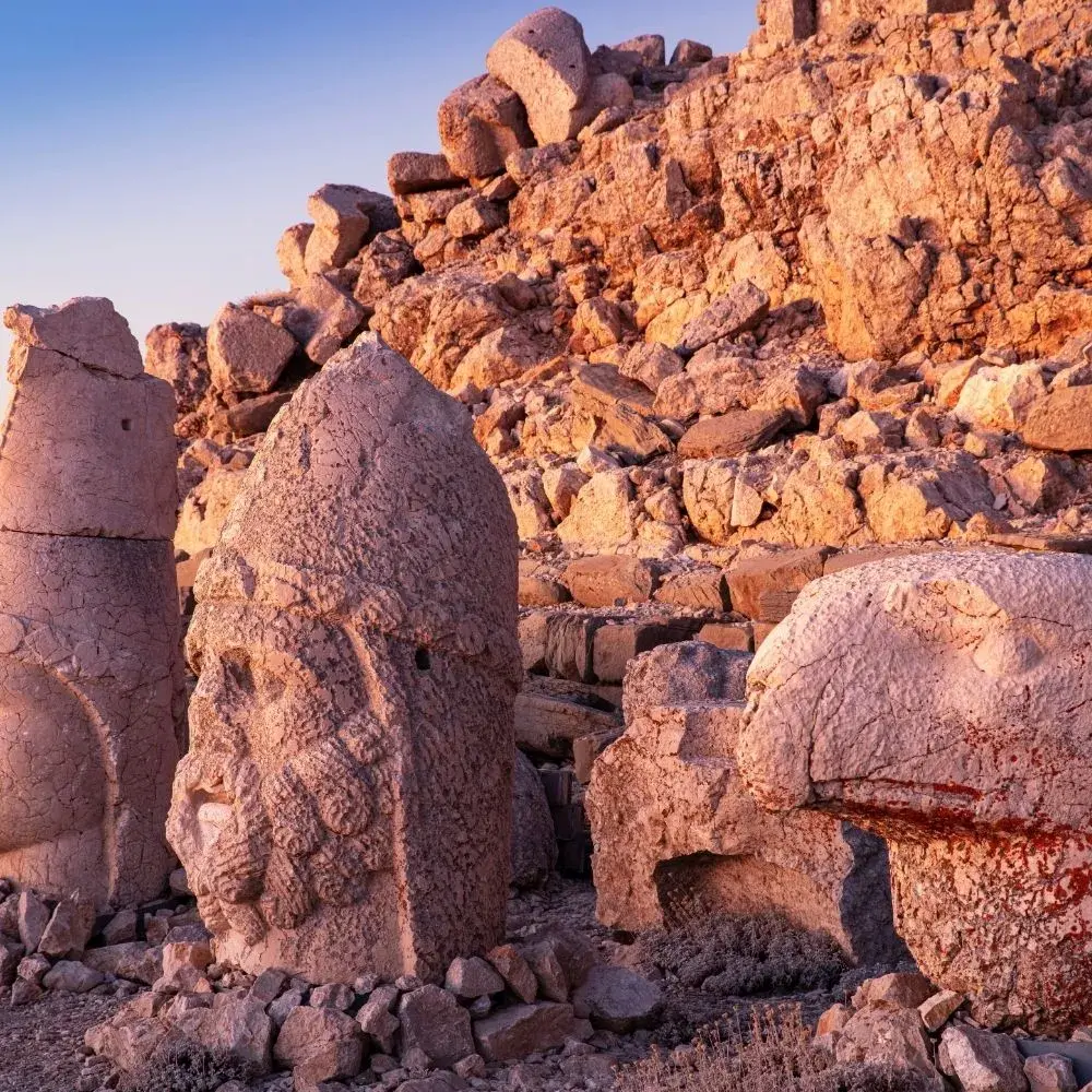 Stone heads on the Mount Nemrut terrace in the sunset light, with the tumulus of stones behind